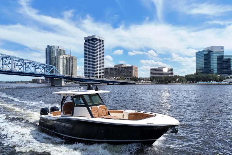 Slide: The Image of 2021 Scout 330 LXF boat cruising near city skyline and bridge on a sunny day. - 94