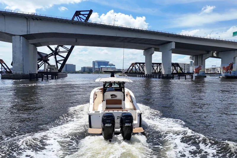 Slide: The Image of 2021 Scout 330 LXF boat cruising under a bridge on a sunny day. - 96