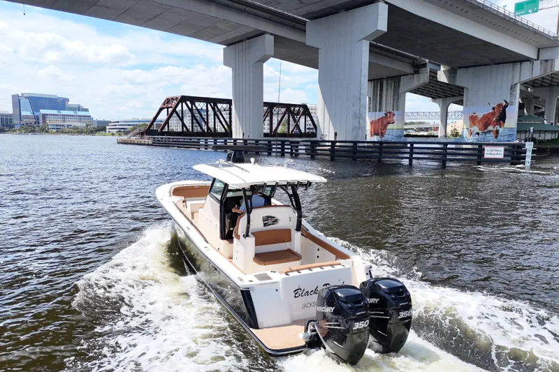 Slide: The Image of 2021 Scout 330 LXF boat cruising under a bridge on a sunny day. - 97
