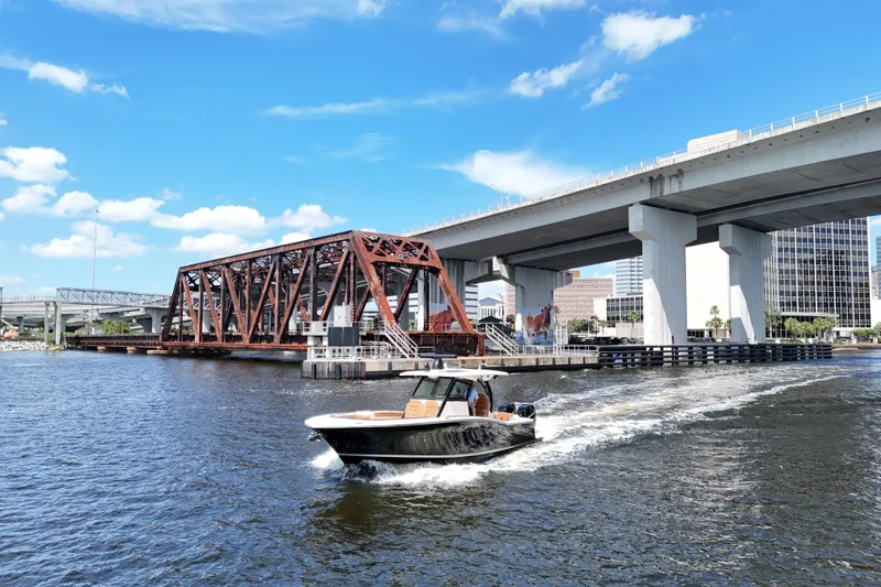 Slide: The Image of 2021 Scout 330 LXF boat cruising under bridges on a sunny day. - 98