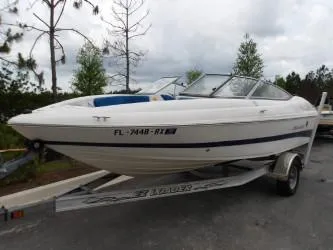 Slide: The Image of 2004 Mariah SK-10 boat on trailer, parked outdoors, with trees in the background. - 2
