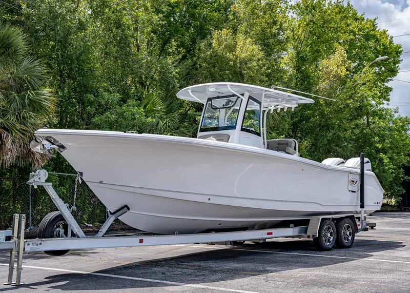 The Image of 2026 Sea Hunt Ultra 305 SE boat on trailer, surrounded by lush greenery. - 1