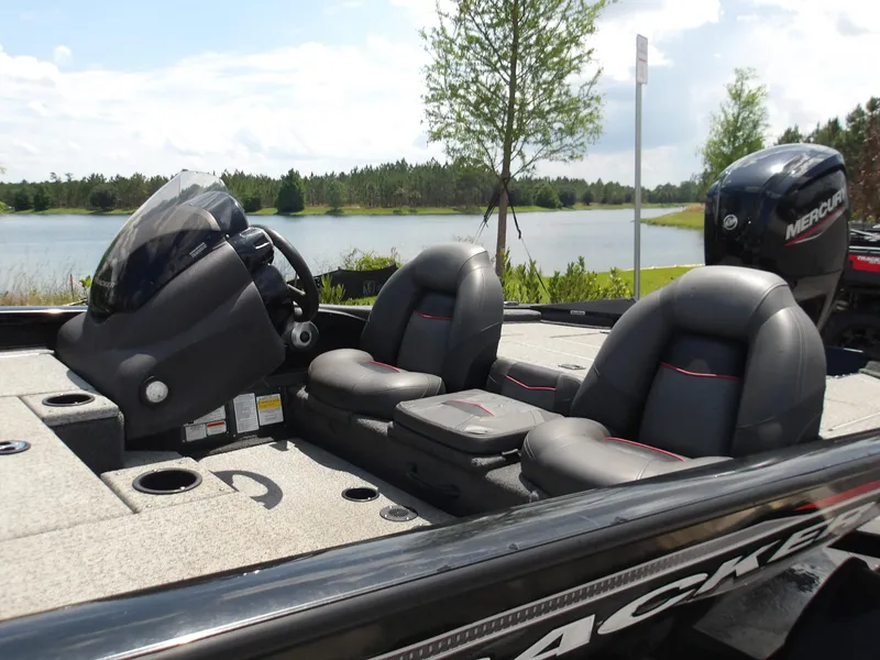 Slide: The Image of 2021 Tracker Pro Team 175 TXW boat interior with seats and steering, near a scenic lake. - 6