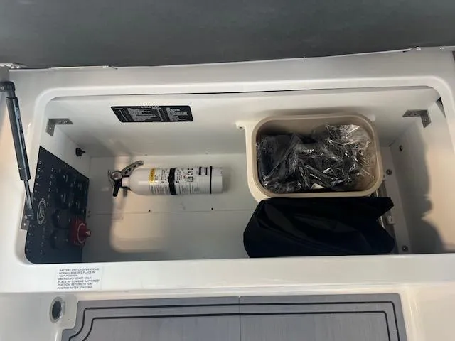 Slide: The Image of Storage compartment in a 2025 Cobalt R6 Surf boat with fire extinguisher and accessories. - 18