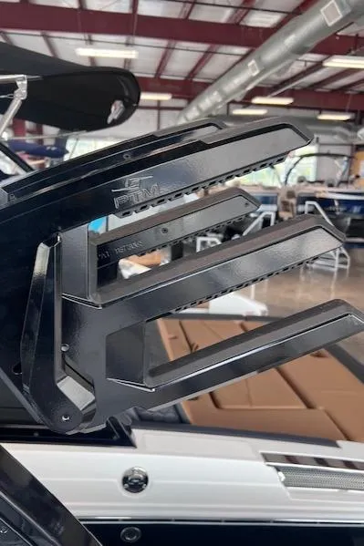 Slide: The Image of 2025 Cobalt R6 Surf boat with black wakeboard rack in a showroom. - 22