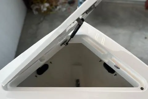 Slide: The Image of 2025 Cobalt R6 Surf boat storage compartment with open lid, showcasing interior space. - 4