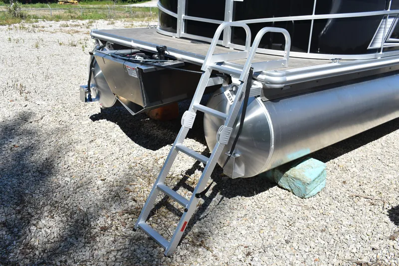 Slide: The Image of 2024 SunChaser Vista 20 Fish pontoon boat with attached ladder on gravel. - 12