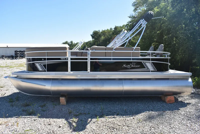 Slide: The Image of 2024 SunChaser Vista 20 Fish pontoon boat on gravel lot with trees in background. - 4