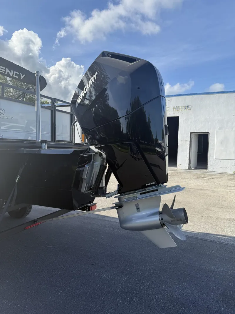 Slide: The Image of 2024 Regency 250 DL3 boat with Mercury outboard motor, parked outdoors. - 11