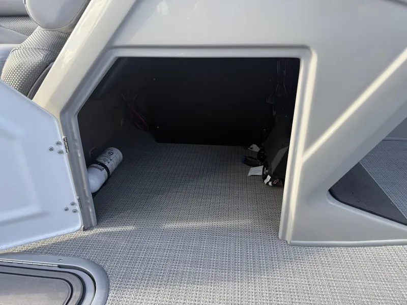 Slide: The Image of Open storage compartment in 2024 Regency 250 DL3 boat, featuring carpeted interior and fire extinguisher. - 21