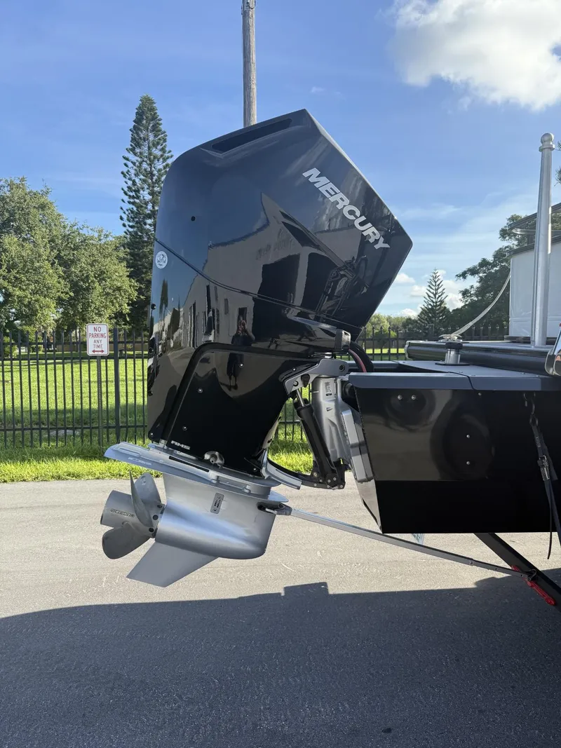 Slide: The Image of 2024 Regency 250 DL3 boat with Mercury outboard motor, parked outdoors. - 9