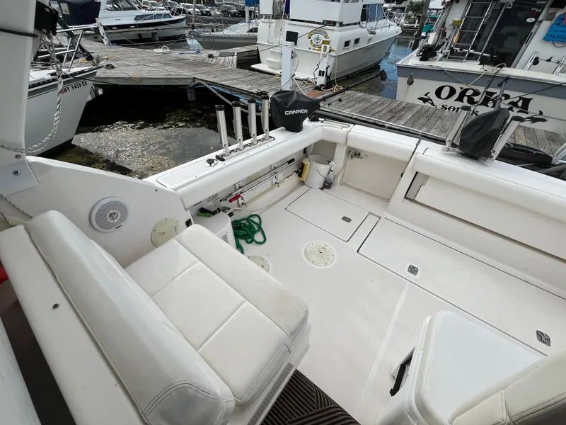 Slide: The Image of 2000 Tiara Yachts 3100 Open boat interior at dock, featuring seating and fishing rod holders. - 27