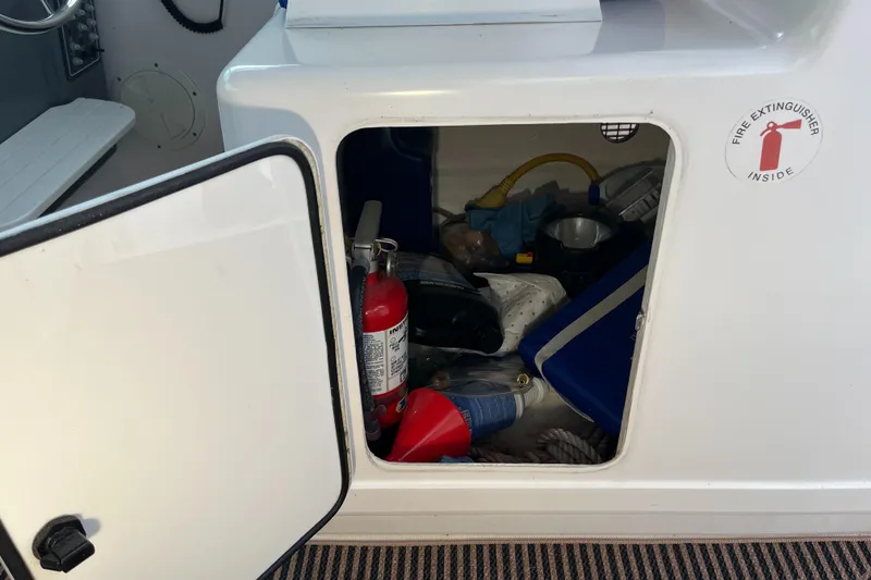 Slide: The Image of Open storage compartment on 2000 Tiara Yachts 3100 Open, containing fire extinguisher and various items. - 9