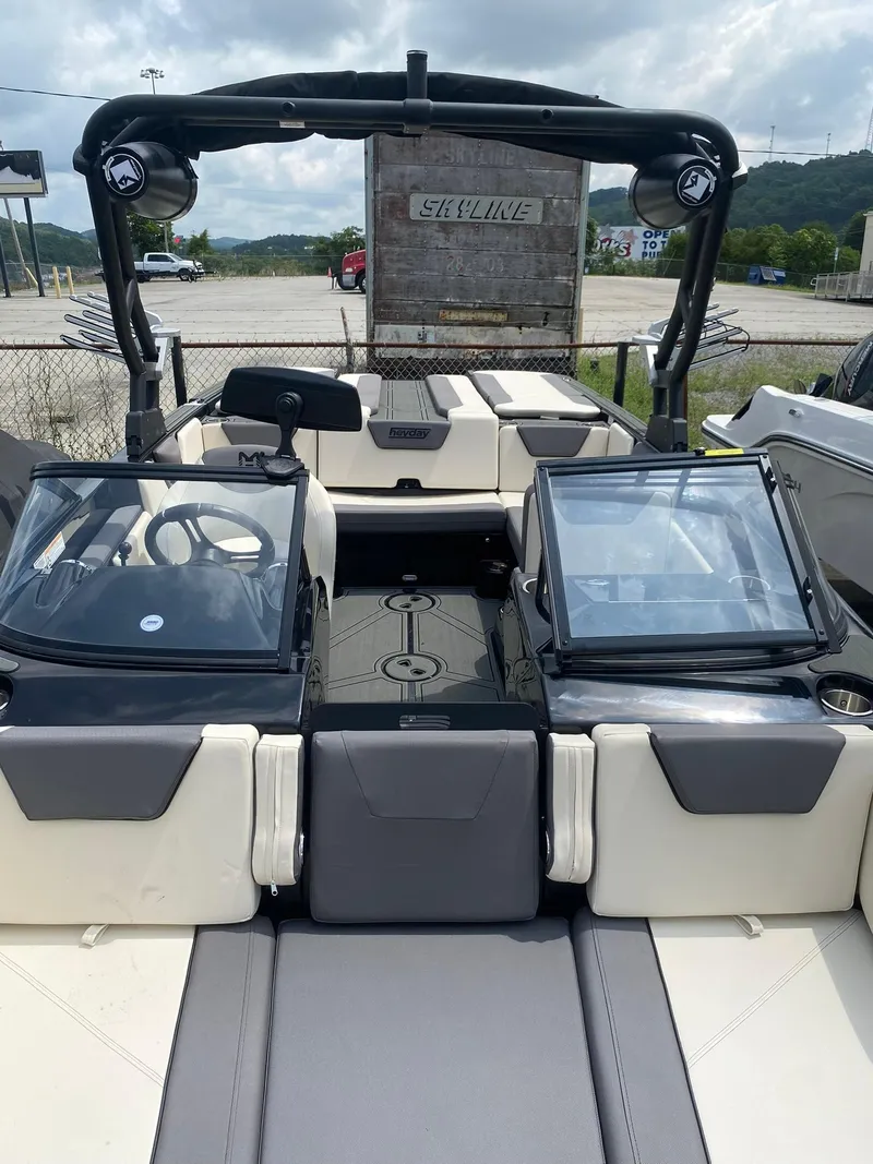 Slide: The Image of 2025 Heyday WTSurf boat interior with dual windshields and seating, parked outdoors. - 11