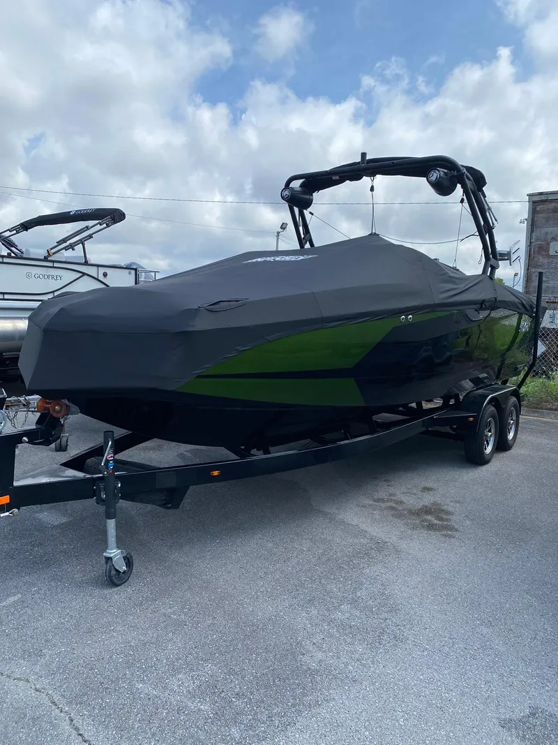 Slide: The Image of 2025 Heyday WTSurf boat covered on trailer, parked outdoors under cloudy sky. - 2