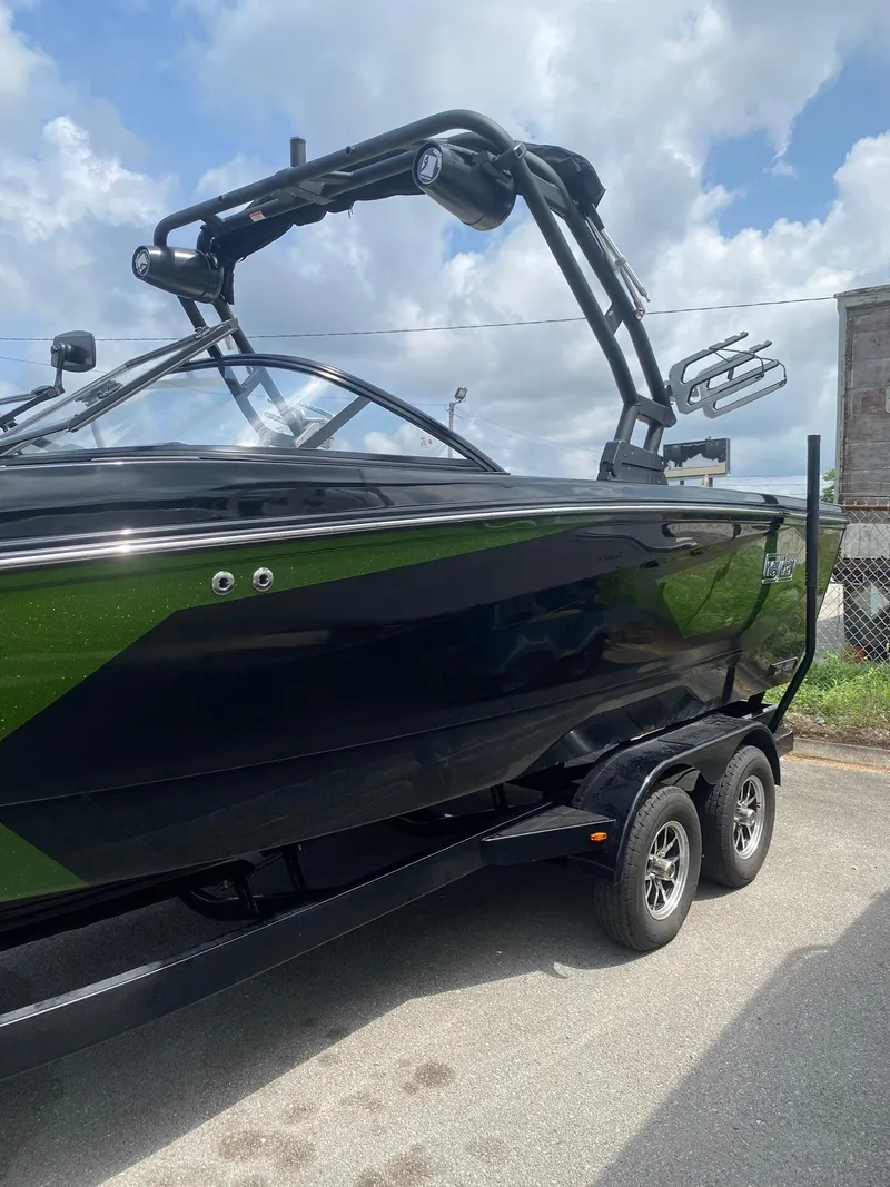 Slide: The Image of 2025 Heyday WTSurf boat on trailer, black and green design, under cloudy sky. - 5
