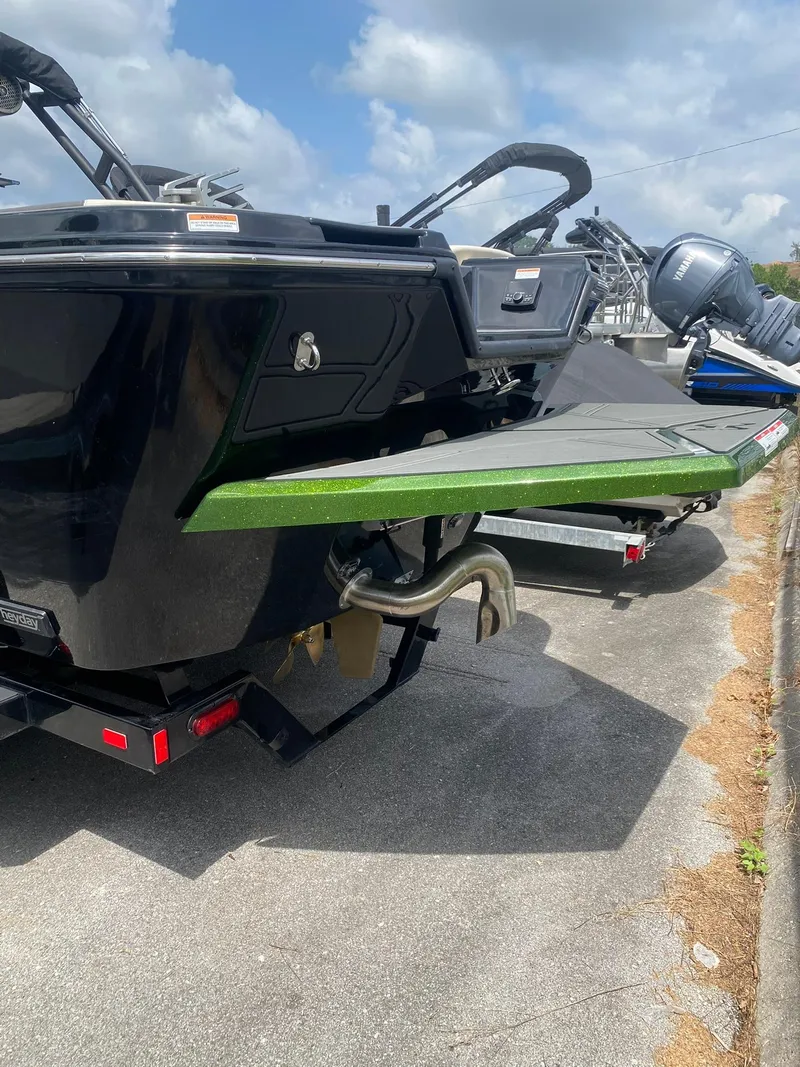 Slide: The Image of 2025 Heyday WTSurf boat rear view with green swim platform and trailer. - 6