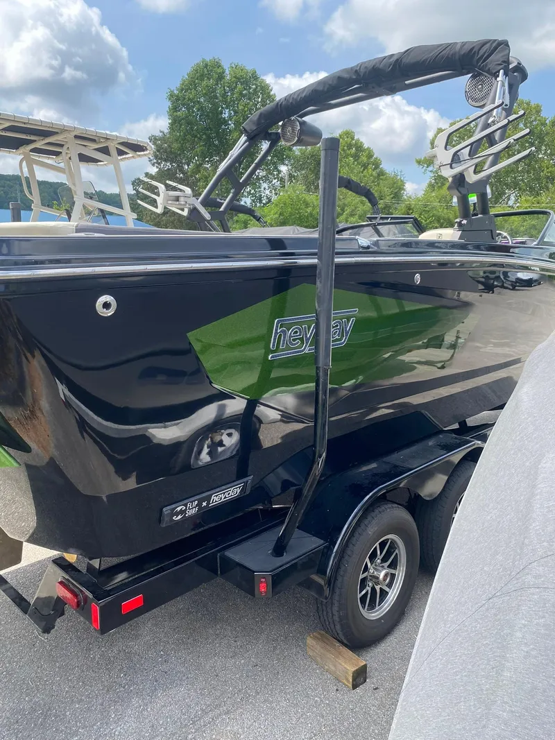 Slide: The Image of 2025 Heyday WTSurf boat on trailer, black and green design, parked outdoors. - 8