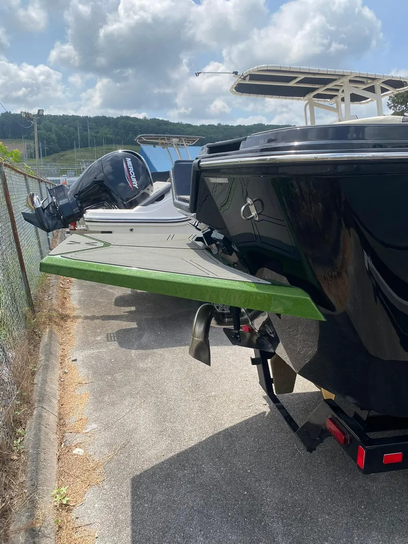 Slide: The Image of 2025 Heyday WTSurf boat with Mercury outboard motor, parked on concrete under cloudy sky. - 9