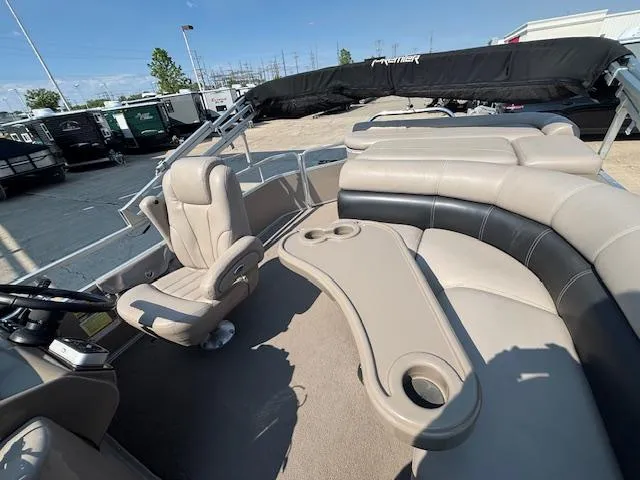 Slide: The Image of 2009 Premier 225 Grand Majestic boat interior with seating and table, parked outdoors. - 12