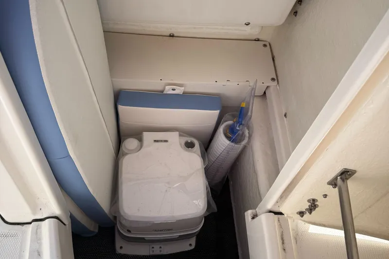 Slide: The Image of 2025 Robalo R200 Center Console boat storage area with portable toilet and cleaning supplies. - 10