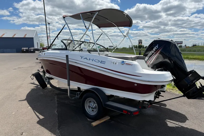 Slide: The Image of 2018 Tahoe 450TF boat on trailer with Mercury outboard motor, parked outdoors under cloudy sky. - 0