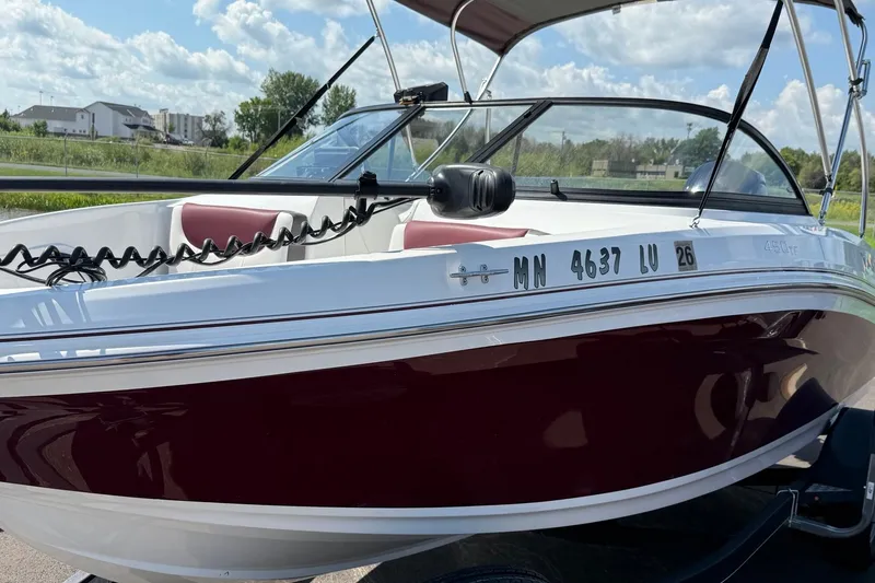 Slide: The Image of 2018 Tahoe 450TF boat with maroon and white exterior, parked outdoors under a blue sky. - 6