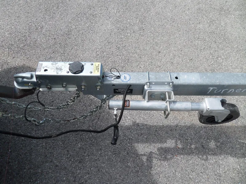 Slide: The Image of Trailer hitch and wheel assembly for 1995 Sea Ray 250 Sundancer on asphalt surface. - 12