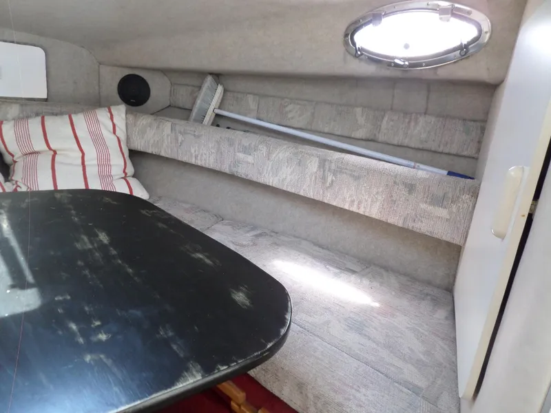 Slide: The Image of 1995 Sea Ray 250 Sundancer cabin interior with table, cushions, and porthole window. - 28