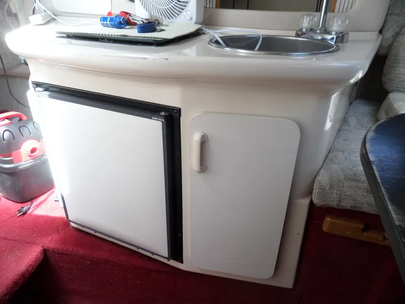 Slide: The Image of 1995 Sea Ray 250 Sundancer interior with kitchenette, featuring a sink and mini fridge. - 30