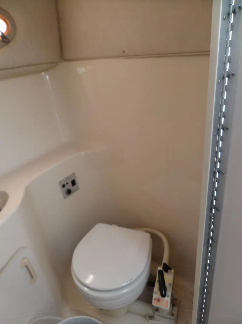 Slide: The Image of 1995 Sea Ray 250 Sundancer boat bathroom with compact toilet and beige interior. - 32