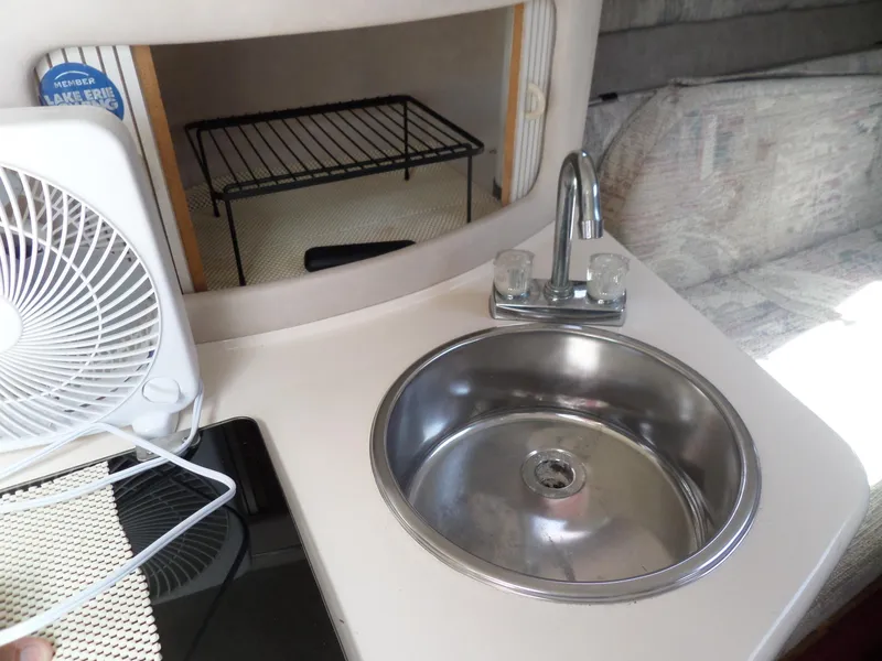 Slide: The Image of 1995 Sea Ray 250 Sundancer interior with sink, faucet, and fan in compact kitchen area. - 38
