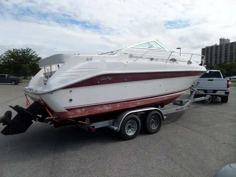 Slide: The Image of 1995 Sea Ray 250 Sundancer boat on trailer, parked outdoors under cloudy sky. - 6