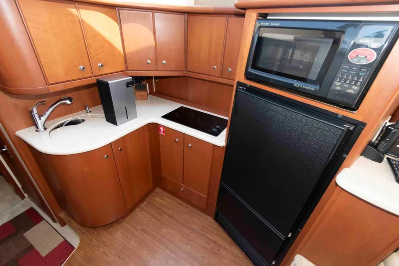 Slide: The Image of 2004 Silverton 34 Convertible yacht kitchen with microwave, sink, and wooden cabinetry. - 18