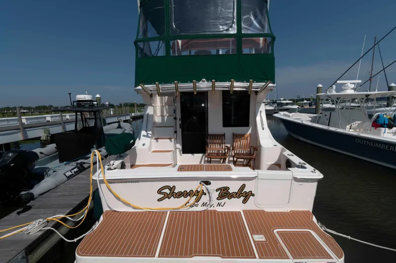 Slide: The Image of 2004 Silverton 34 Convertible yacht docked, featuring wooden deck and green canopy. - 2