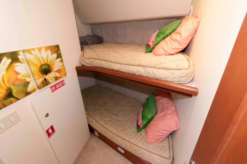Slide: The Image of 2004 Silverton 34 Convertible cabin with bunk beds, floral decor, and life jacket storage. - 21