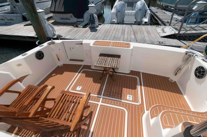 Slide: The Image of 2004 Silverton 34 Convertible yacht deck with wooden chairs and table at marina. - 3