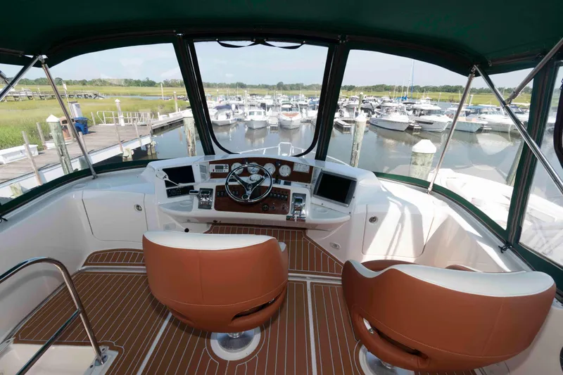 Slide: The Image of Interior view of 2004 Silverton 34 Convertible yacht helm with marina backdrop. - 7