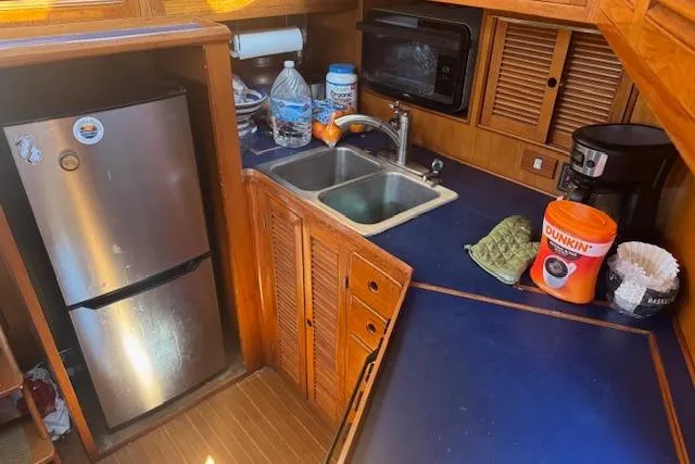 Slide: The Image of 1985 Spindrift Trawler kitchen with sink, fridge, microwave, and coffee maker on blue countertop. - 10