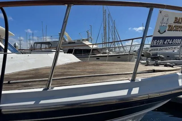 Slide: The Image of 1985 Spindrift Trawler docked at marina, wooden deck, clear sky, sailboats in background. - 20
