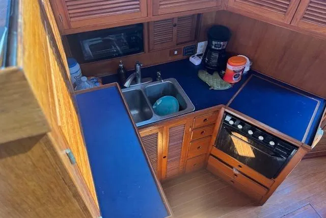 Slide: The Image of 1985 Spindrift Trawler kitchen with blue countertops, sink, stove, and wooden cabinets. - 8