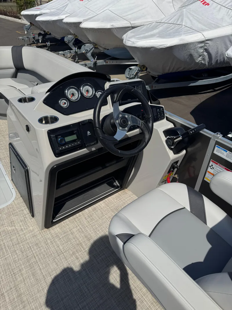 Slide: The Image of 2025 SunCatcher Select 324SL boat interior with steering wheel and dashboard controls. - 6
