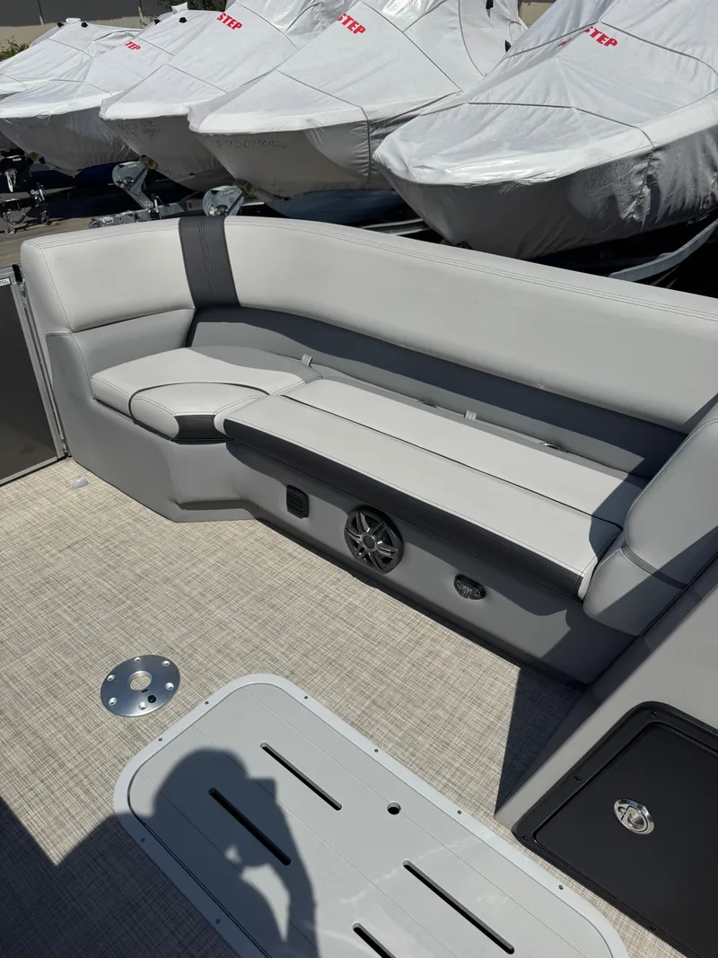 Slide: The Image of 2025 SunCatcher Select 324SL boat interior with gray seating and covered boats in background. - 7
