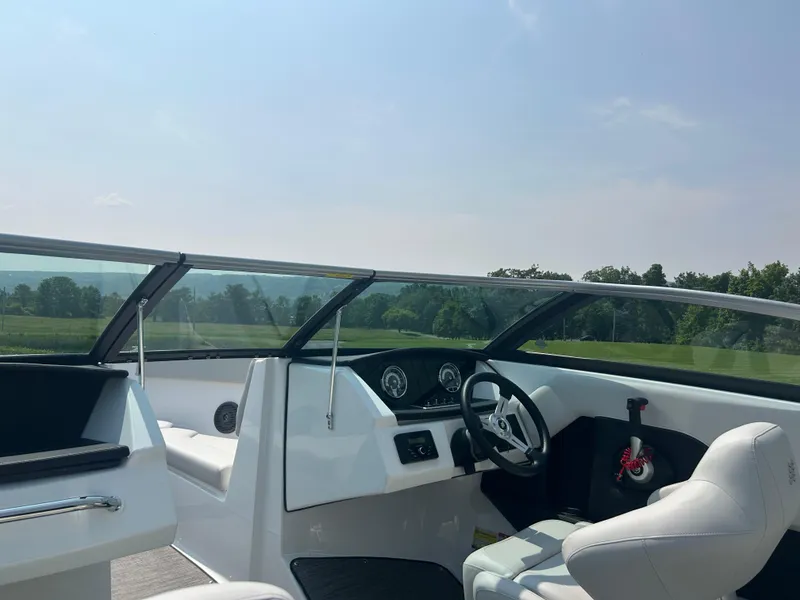 Slide: The Image of 2026 Four Winns H4 Freedom boat interior with steering wheel and dashboard, set against a scenic backdrop. - 8