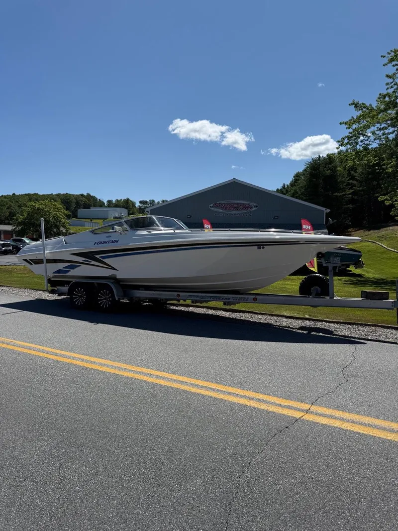 Slide: The Image of 2002 Fountain 29 Fever boat on trailer, parked near a building under a clear blue sky. - 1