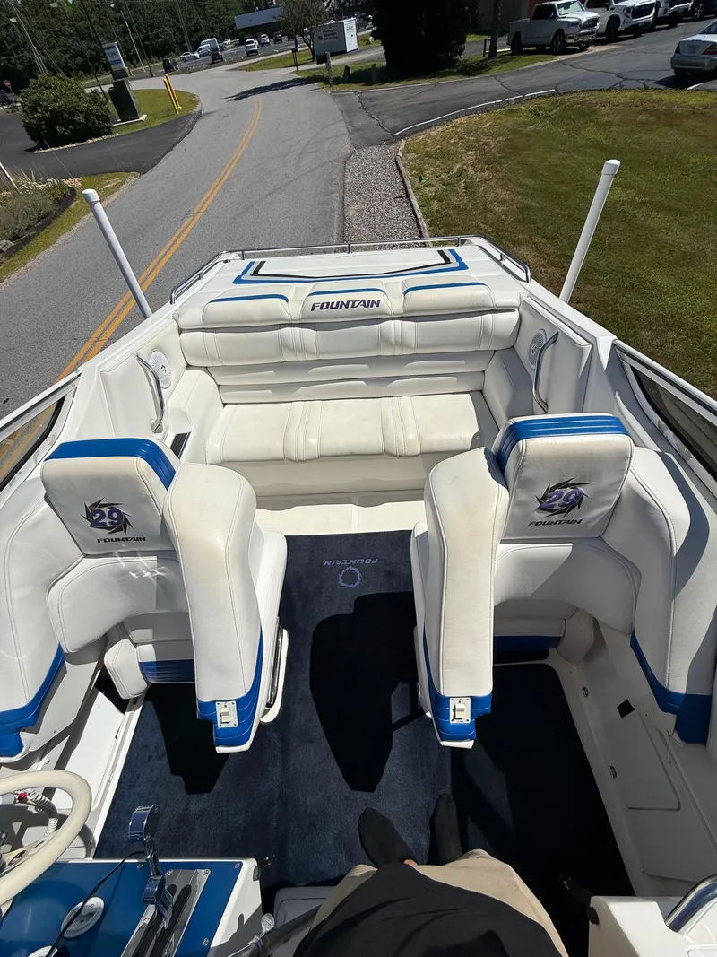 Slide: The Image of 2002 Fountain 29 Fever boat interior with white and blue seating, parked on a road. - 4