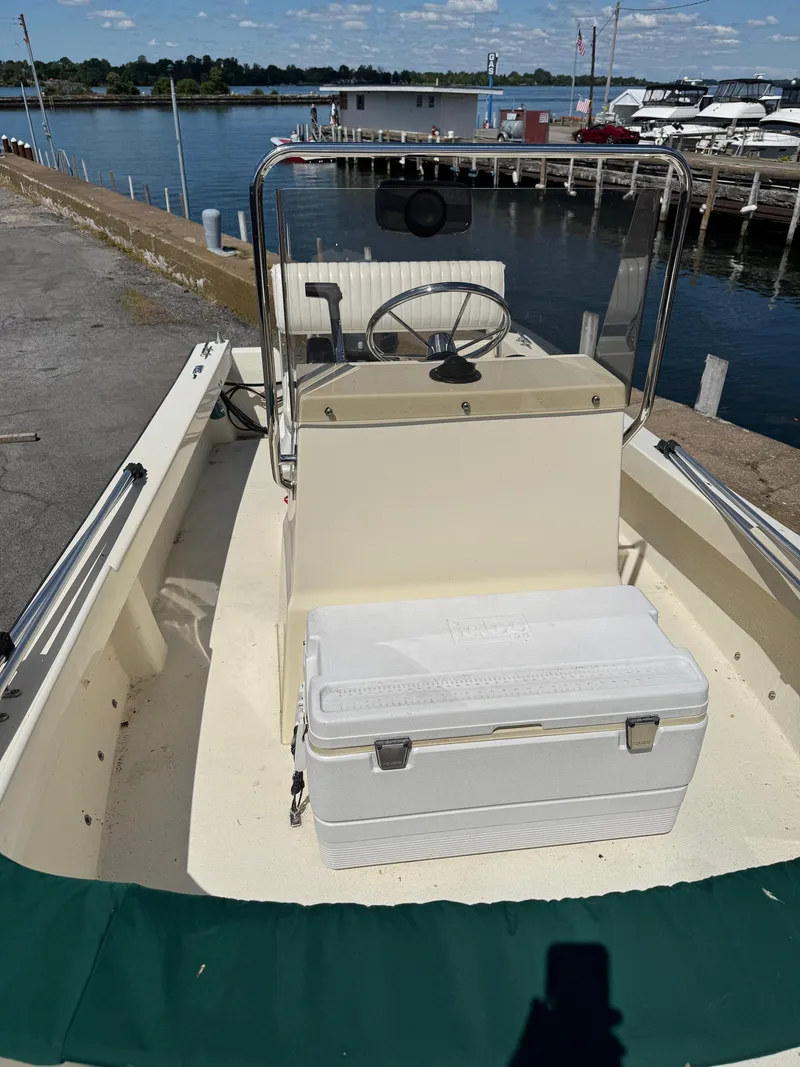 Slide: The Image of 2014 Eastern 19 boat docked by a marina, featuring a steering console and cooler. - 13