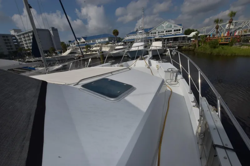 Slide: The Image of 1998 Hatteras 74 Sport Deck yacht docked at a marina under a partly cloudy sky. - 2