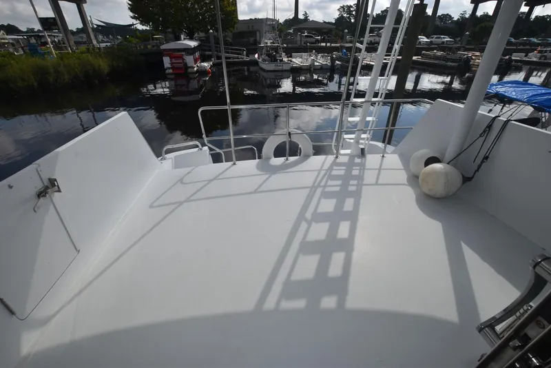 Slide: The Image of 1998 Hatteras 74 Sport Deck yacht stern view at marina, featuring spacious deck area. - 5