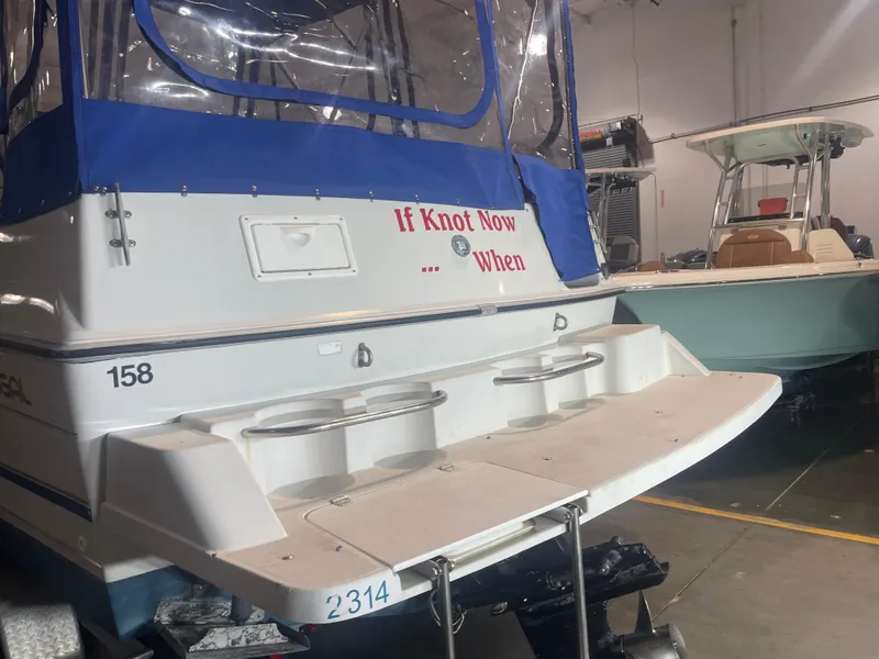 Slide: The Image of 1993 Regal Ambassador 233 boat with blue canopy and motivational text in a storage facility. - 11